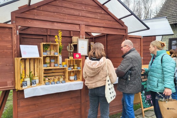 Klienci oglądają produkty przy stoisku z produktami Pasieki św. Ambrożego