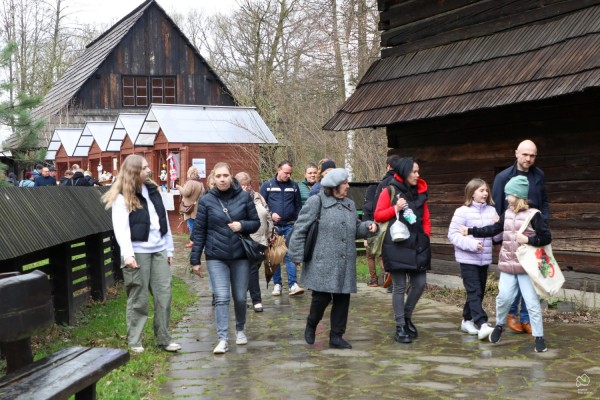 Ludzie spacerujący na terenie skansenu, w tle stoiska z lokalnymi produktami