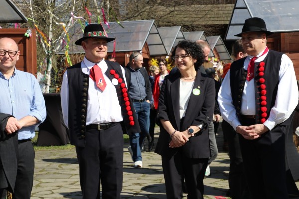 Przedstawiciele Gminy Pszczyna, Powiatu Pszczyńskiego oraz Komisji Certyfikacyjnej na terenie skansenu, gdzie organizowany był festiwal. W tle stoiska z lokalnymi produktami.