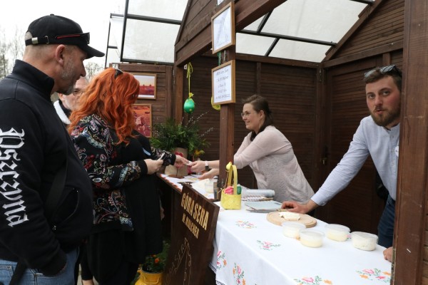 Klienci oglądają produkty na stoiskach podczas jarmarku w skansenie.