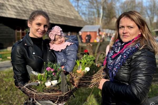 Kobiety z dzieckiem na terenie skansenu prezentują ozdoby wielkanocne zrobione na warsztatach florystycznych.