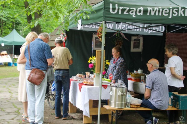 Osoby zainteresowane oglądają lokalne produkty na stoisku.