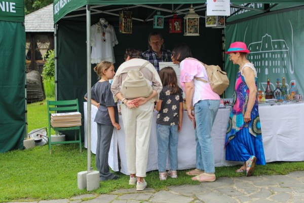 Osoby zainteresowane oglądają lokalne produkty na stoisku.